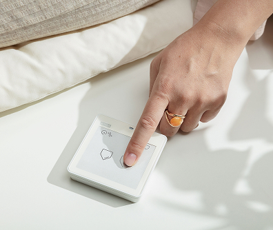 Hand holding VELUX remote control for operating Skylight System shades and venting skylights