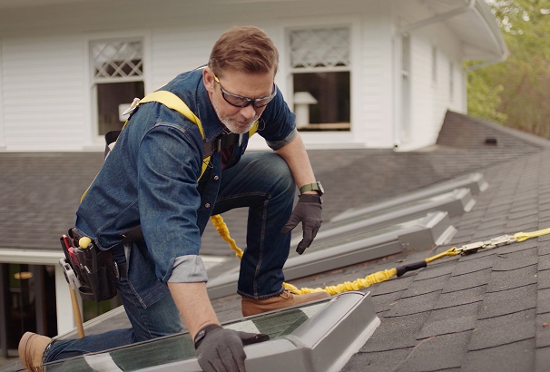 Man on roof installing skylight